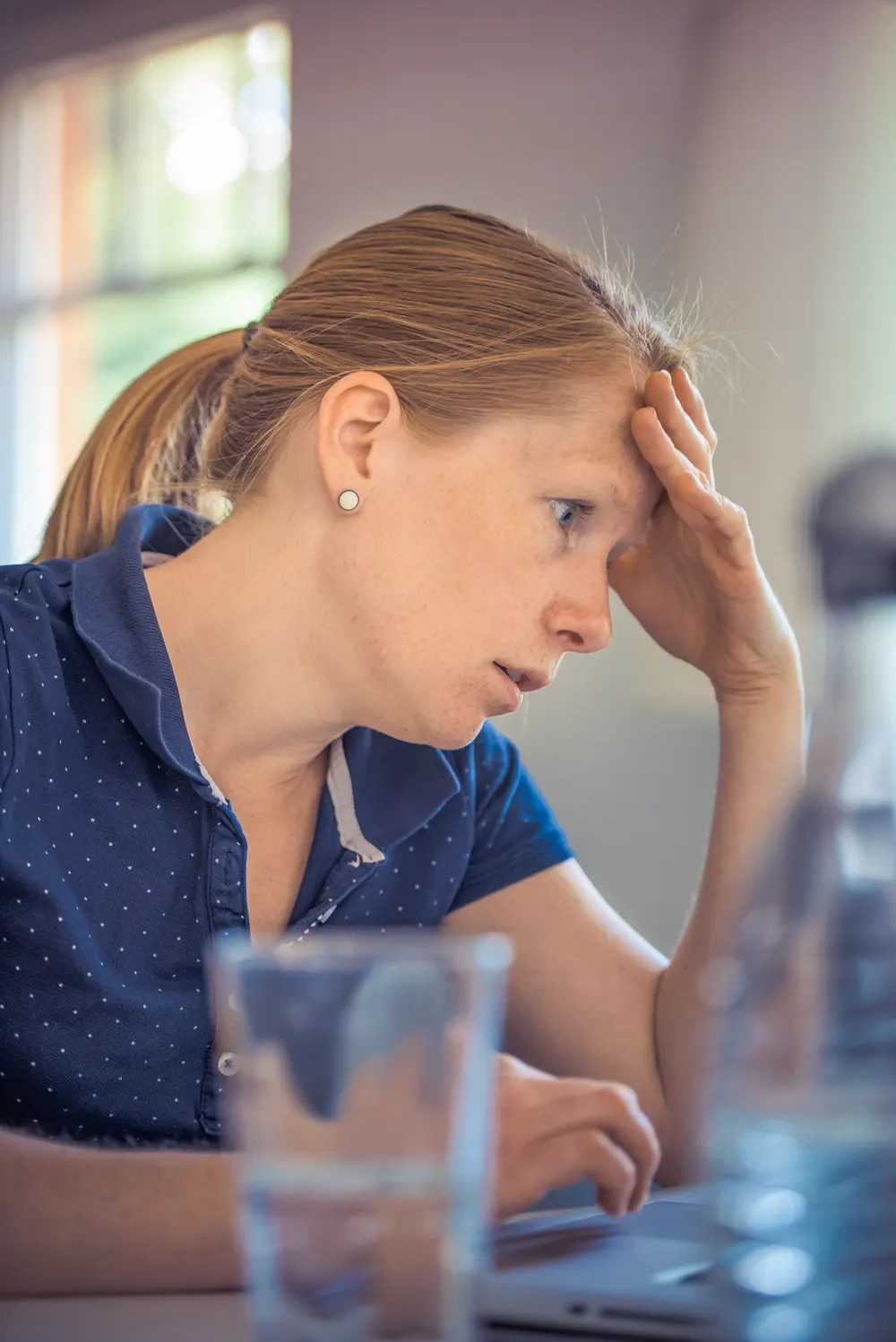 A business owner holding her head while working late at a laptop